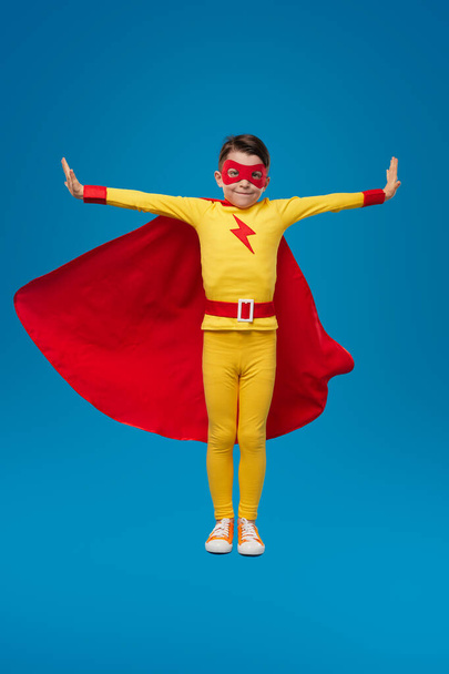 Smiling superhero child in costume in studio - Фото, изображение