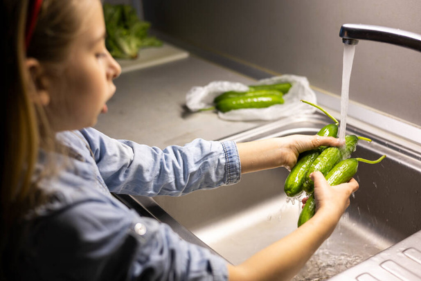 mani di bambini che lavano il cetriolo in cucina - Foto, immagini