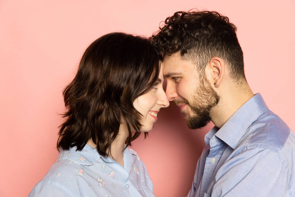 Closeup young and happy man and woman look at each other isolated on pink trendy color background. Human emotions, youth, love and lifestyle concept - Фото, зображення