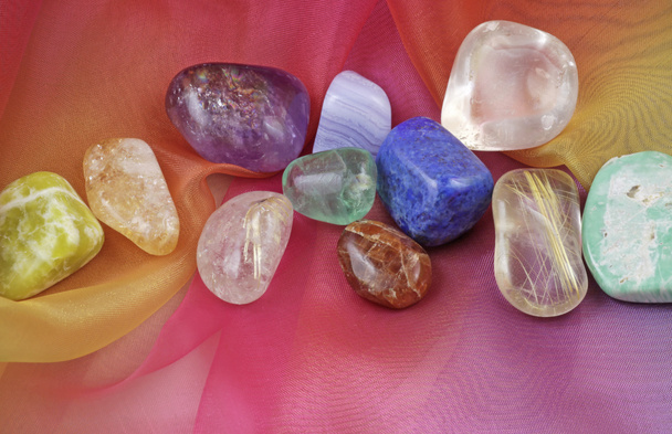 Close up of chakra gemstones on rainbow colored chiffon material - Photo, Image