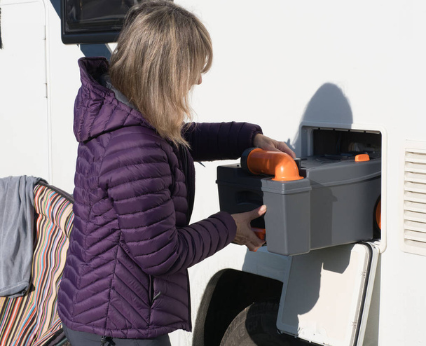 Una mujer homer motor mueve el casete del inodoro de su vehículo recreativo de autocaravanas armario, RV. - Foto, imagen