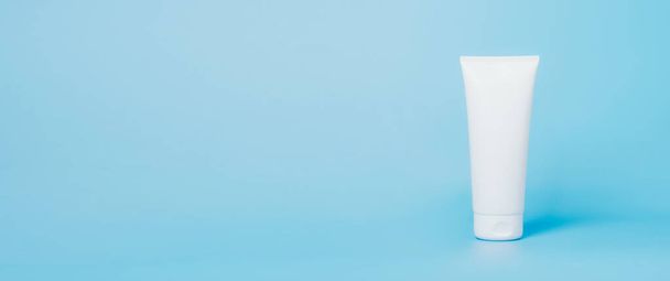 Косметический продукт в трубке, белый контейнер синий фон. Шампунь, крем для рук, белая зубная паста - Фото, изображение