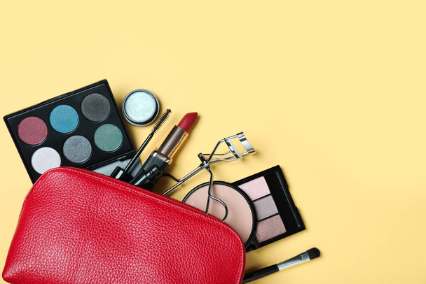Cosmetic bag with makeup products and accessories on yellow background, flat lay. Space for text - Φωτογραφία, εικόνα