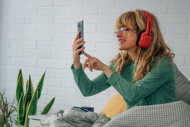 woman at home with mobile phone and headphones - Foto, Bild