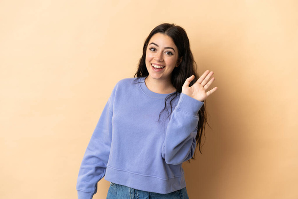 Young caucasian woman over isolated background saluting with hand with happy expression - Foto, Imagen