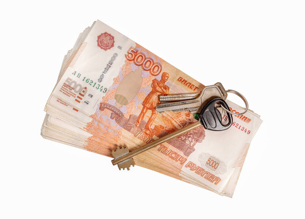 Sada klíčů od domu nebo bytu a svazek velkých peněz.Izolované na bílém pozadí. - Fotografie, Obrázek
