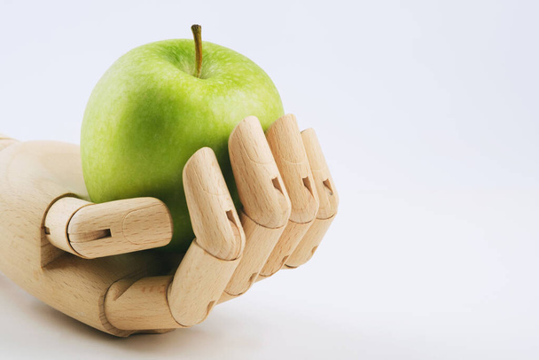 A wooden hand holding a granny smith apple on a white background. - Fotoğraf, Görsel