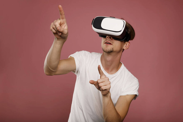 Young Man wearing virtual reality goggles over pink background. 3D virtual lifestyle concept - Photo, image