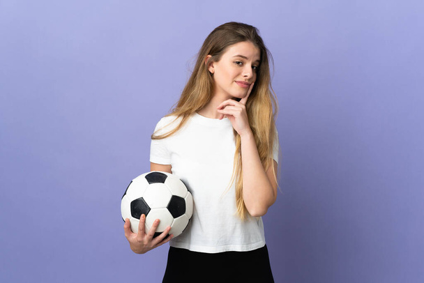 Junge blonde Fußballerin isoliert auf lila Hintergrund mit Zweifeln beim Blick nach oben - Foto, Bild