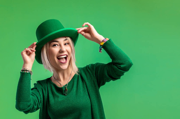 St. Patrick's Day. Beautiful smiling woman wearing green hat. Green background - Photo, Image