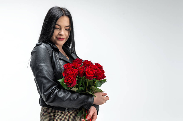 Gyönyörű barna nő, kezében egy csokor vörös rózsával. Valentin-nap és nemzetközi nőnap, március 8. Fehér háttér - Fotó, kép