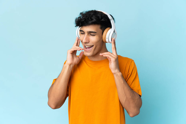 Nuori argentiinalainen mies eristetty taustalla kuuntelee musiikkia ja laulaa - Valokuva, kuva