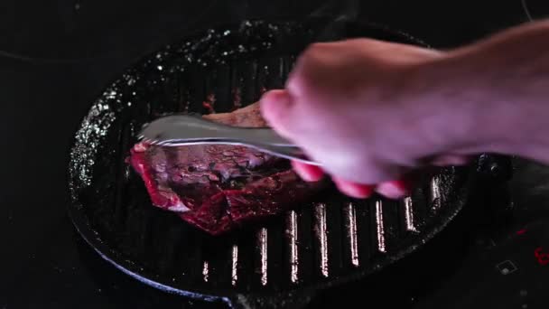 Rindersteak dampfend in einer Pfanne auf einer Induktionsplatte garen - Filmmaterial, Video