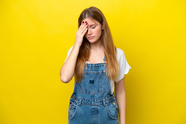 Young caucasian woman isolated on yellow background with headache - Foto, Imagem