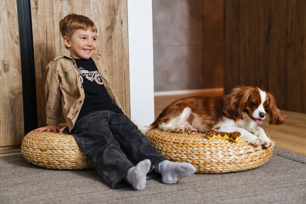 Bambino felice che gioca con il suo cane a casa su un pavimento - Foto, immagini