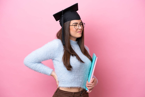 若い学生ブラジル人女性を身に着けている卒業帽子ピンクの背景に孤立した痛みのために努力した - 写真・画像