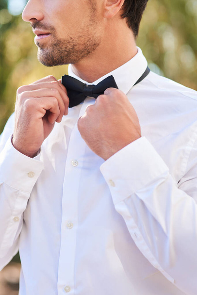 Now Im ready. Cropped shot of an unrecognizable young bridegroom putting on a bowtie while standing outdoors on his wedding day. - Foto, immagini