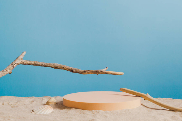 Vuoto podio piattaforma rotonda beige e ramoscelli albero secco su sfondo sabbia bianca spiaggia. Minimo sfondo composizione creativa per cosmetici o prodotti di presentazione con sfondo blu. Vista frontale - Foto, immagini