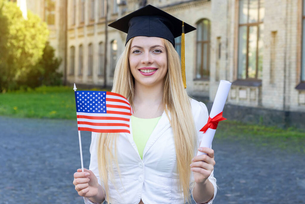 Graduate student with US flag and diploma. Graduation day on the campus of the university. - Foto, Imagem
