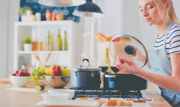 Mooie jonge vrouw koken in keuken thuis - Foto, afbeelding