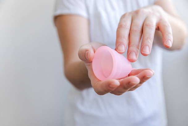 Woman hand holding pink menstrual cup isolated on white background. Woman modern alternative eco gynecological hygiene in menstruation period. Container for blood in girl hand. - Φωτογραφία, εικόνα