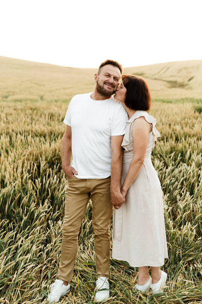 retrato de una pareja de mediana edad en la naturaleza. marido y mujer están sonriendo lindo mientras que en el campo en la parte posterior del día - Foto, imagen