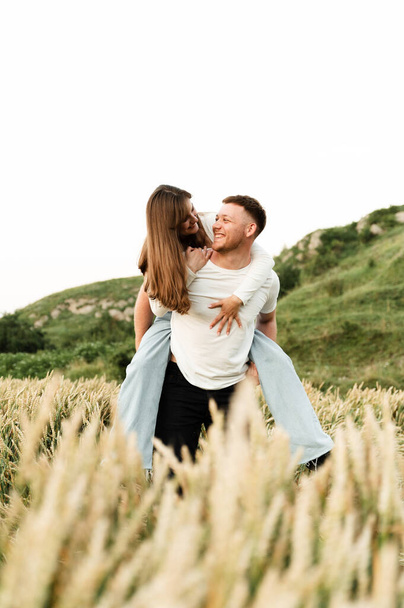 lovers in a wheat field play and laugh. romantic relationship of a modern couple. lovers walk in nature. - Photo, image