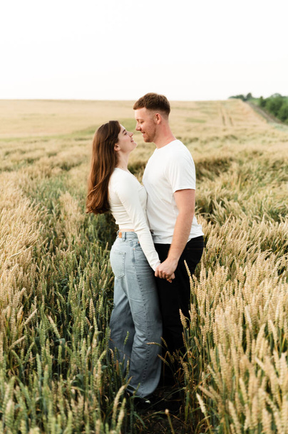 lovers in a wheat field play and laugh. romantic relationship of a modern couple. lovers walk in nature. - Fotoğraf, Görsel
