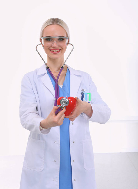 Young woman doctor holding a red heart, isolated on white background. Woman doctor - 写真・画像