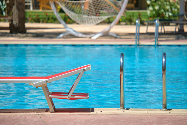 Prázdné lehátko na straně bazénu v letním letovisku. Koncept dovolené a útěku - Fotografie, Obrázek