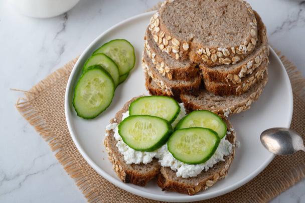 Slices of rye bread with cottage cheese and cucumbers on white background - Photo, Image