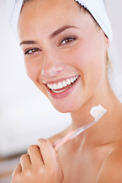 Cuidado con la placa. Una mujer hermosa sosteniendo un cepillo de dientes y mostrando una sonrisa perfecta. - Foto, imagen