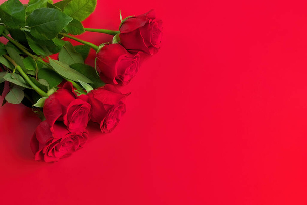 Ακριβώς πάνω από overhead άποψη του κόκκινου τριαντάφυλλου μπουκέτο σε ένα κόκκινο φόντο. Αντιγραφή χώρου δεξιά. - Φωτογραφία, εικόνα