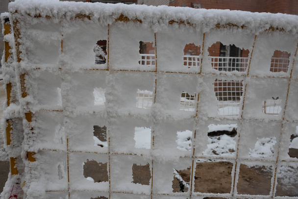 The fence grid is strewn with frost crystals, snowflakes. Winter snowy frosty background. World Snow Day. - Photo, Image