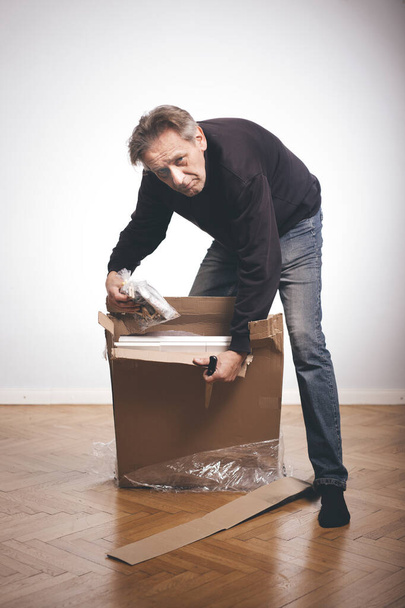 Man unpacking paper box with set of three laminated wood drawers  - Foto, immagini