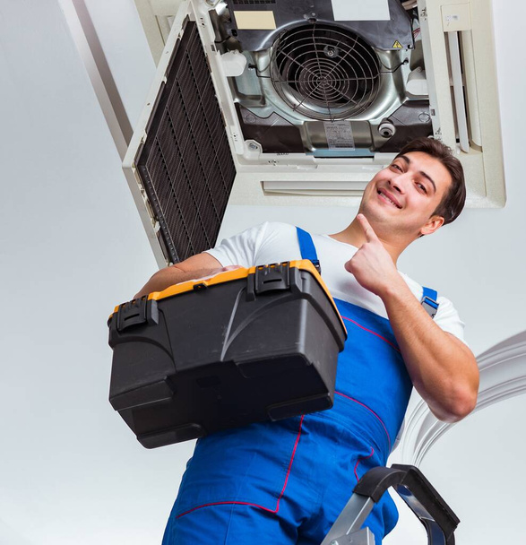 Worker repairing ceiling air conditioning unit - Photo, Image