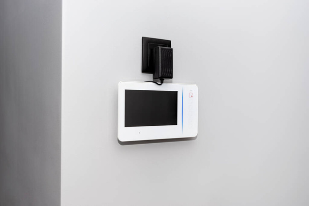 Відеотелефон, встановлений на стіні з вимкненим чорним екраном, видимий блок живлення з кабелем
. - Фото, зображення