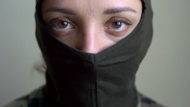 Retrato femenino de una joven vestida con pasamontañas caqui, solo son visibles los ojos, conscripción obligatoria, militar, feminismo, concepto de igualdad - Metraje, vídeo