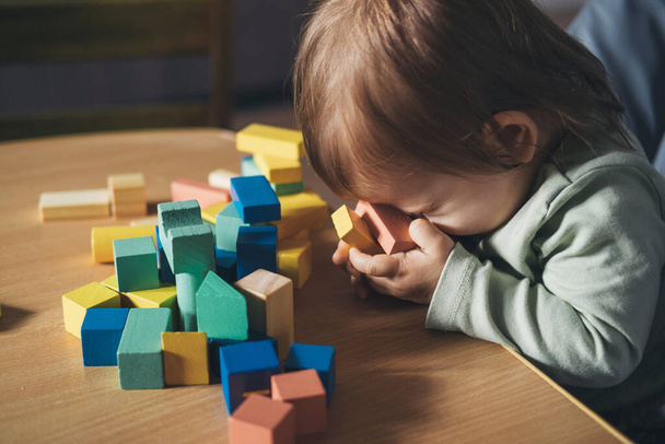 Малышка, сидящая в высоком кресле в игровой комнате и играющая с игрушками. Развитие ребенка. - Фото, изображение