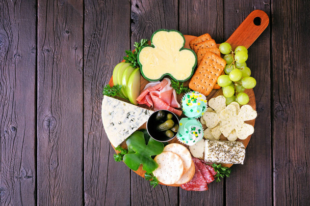 St. Patricks Day Thema Wurstplatte vor einem Holzhintergrund. Verschiedene Vorspeisen aus Käse, Fleisch, Obst und Gemüse. Gesamtübersicht. - Foto, Bild