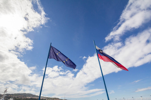 Σημαίες της Ευρωπαϊκής Ένωσης και της Σλοβενίας παραιτούνται από κοινού στη σλοβενική πόλη Koper Η Σλοβενία είναι μέλος της ΕΕ από το 2004 και σημαντικός παράγοντας του ευρωπαϊκού παιχνιδιού. - Φωτογραφία, εικόνα