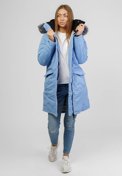 young woman in winter clothes on white background. Photo concept for advertising a down jacket - Zdjęcie, obraz