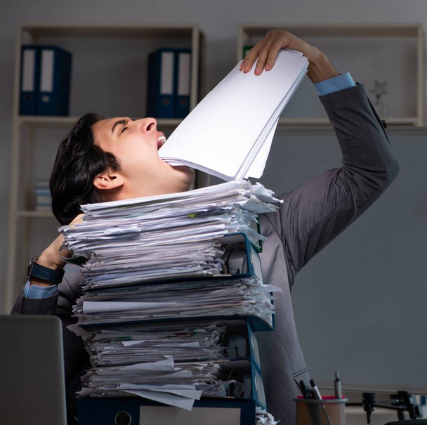 El joven empleado que trabaja hasta tarde en la oficina
 - Foto, Imagen