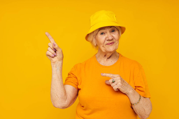 elderly woman in casual t-shirt yellow panama isolated background - 写真・画像