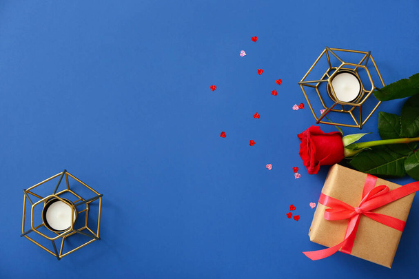 Valentijnsdag cadeau, roos en kaarsen op kleur achtergrond - Foto, afbeelding