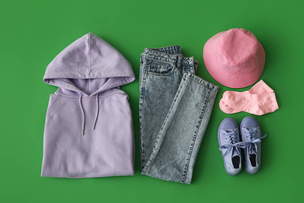 Stylish female clothes with accessories and sneakers on green background - Photo, Image