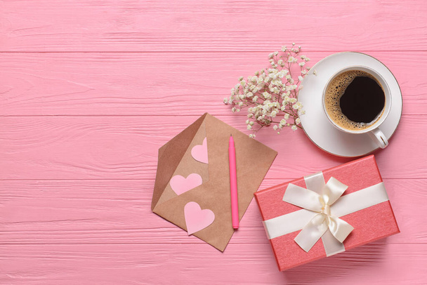 Δώρο για την Ημέρα του Αγίου Βαλεντίνου, φλιτζάνι καφέ και φάκελο σε ροζ ξύλινο φόντο - Φωτογραφία, εικόνα