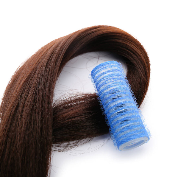 Lange brünette Haare mit Lockenwickler auf hellem Hintergrund, Nahaufnahme - Foto, Bild
