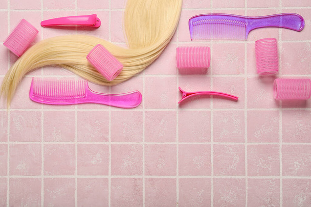 Σετ εργαλείων κομμωτηρίου, μπικουτί και μακριά ξανθά μαλλιά σε ροζ φόντο - Φωτογραφία, εικόνα