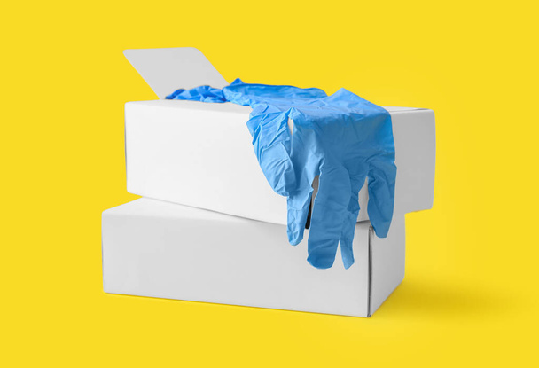 Caixas de papel com luvas médicas em fundo amarelo - Foto, Imagem